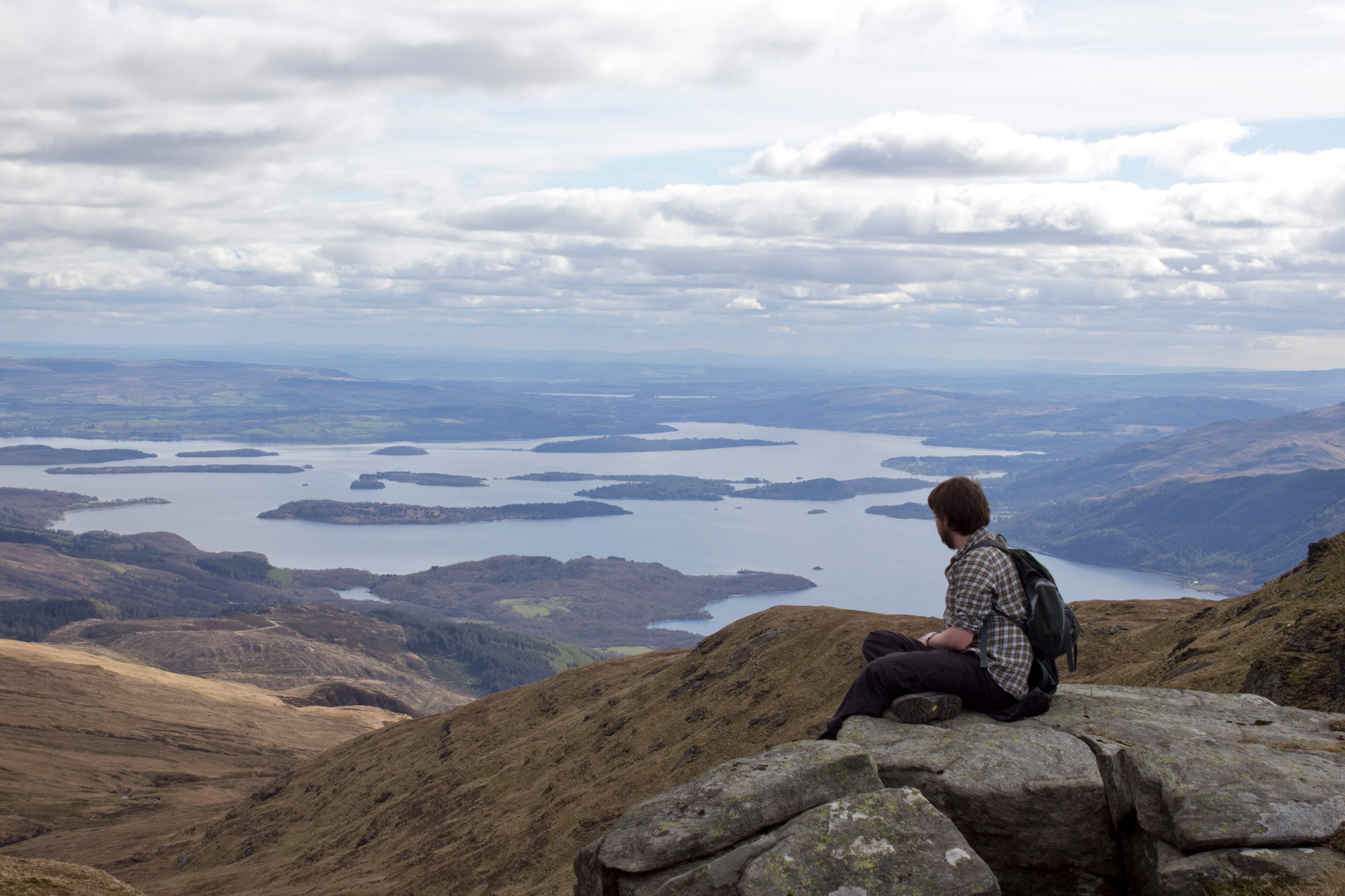 A walker enjoys the view from the top of Ben Lomond