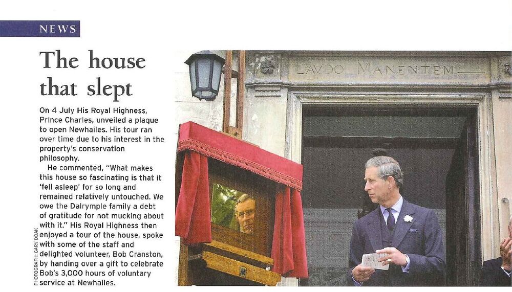 A snippet from a magazine, featuring a story about the then Prince Charles opening Newhailes House. The photo shows Charles standing beneath an old stone lintel next to a shiny brass plaque. The plaque reflects Charles's face. It has little red curtains either side.
