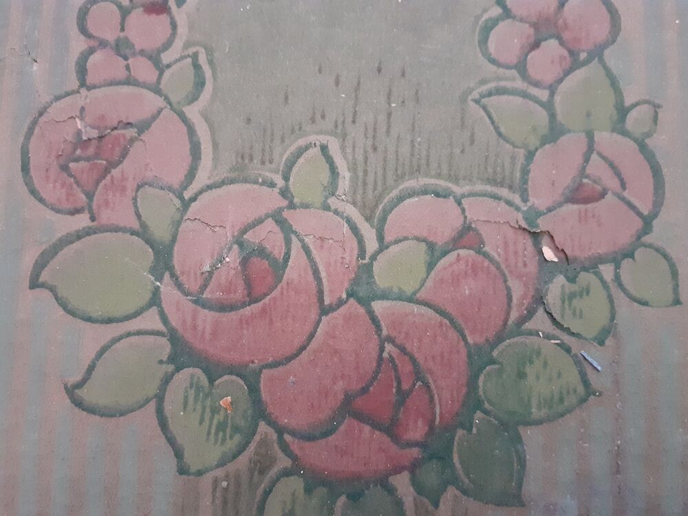 A close-up of an old section of wallpaper, showing Glasgow Style pink roses in a pale stripy background.