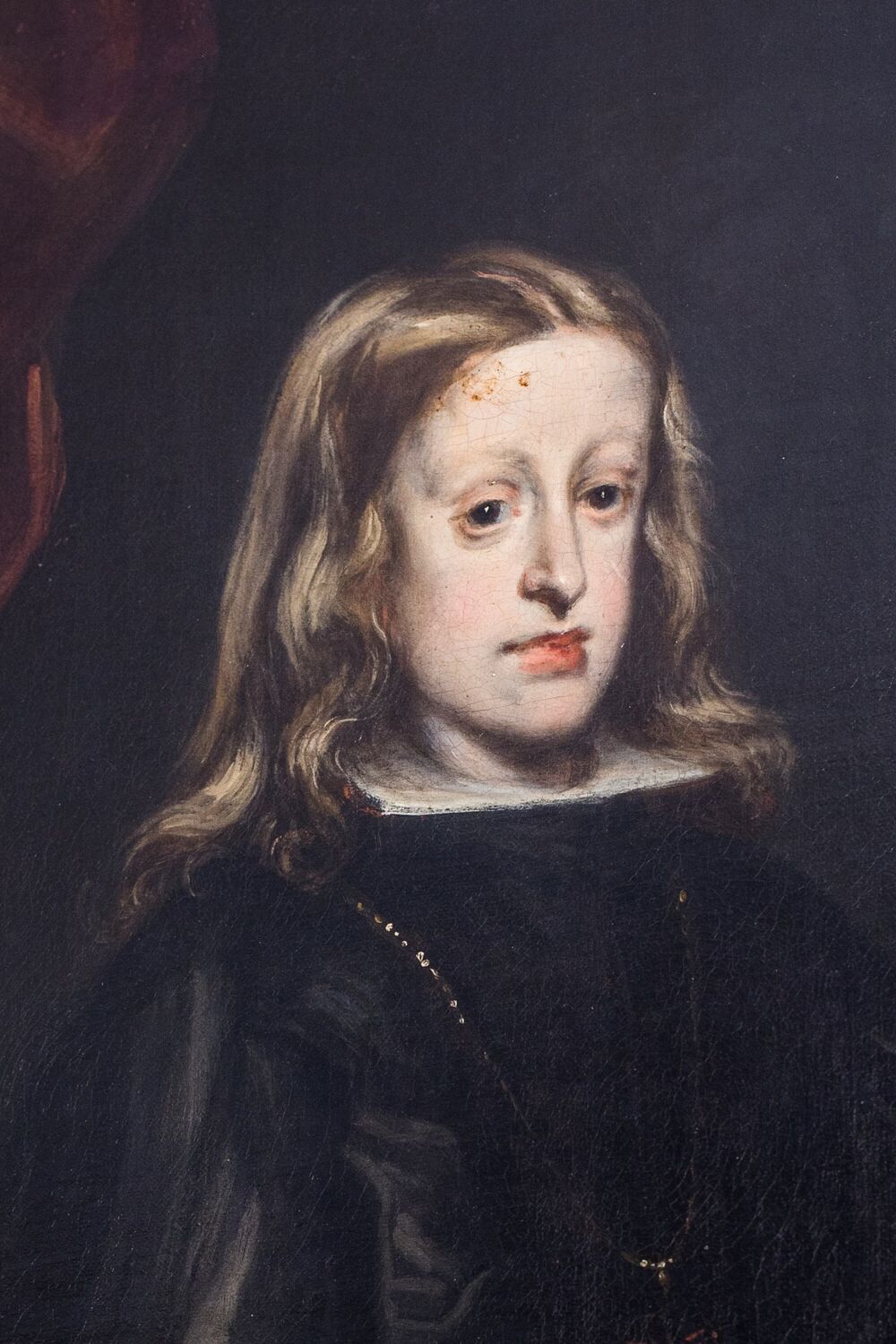 Portrait of a boy with long brown hair. He has an elongated face with a pronounced jaw.