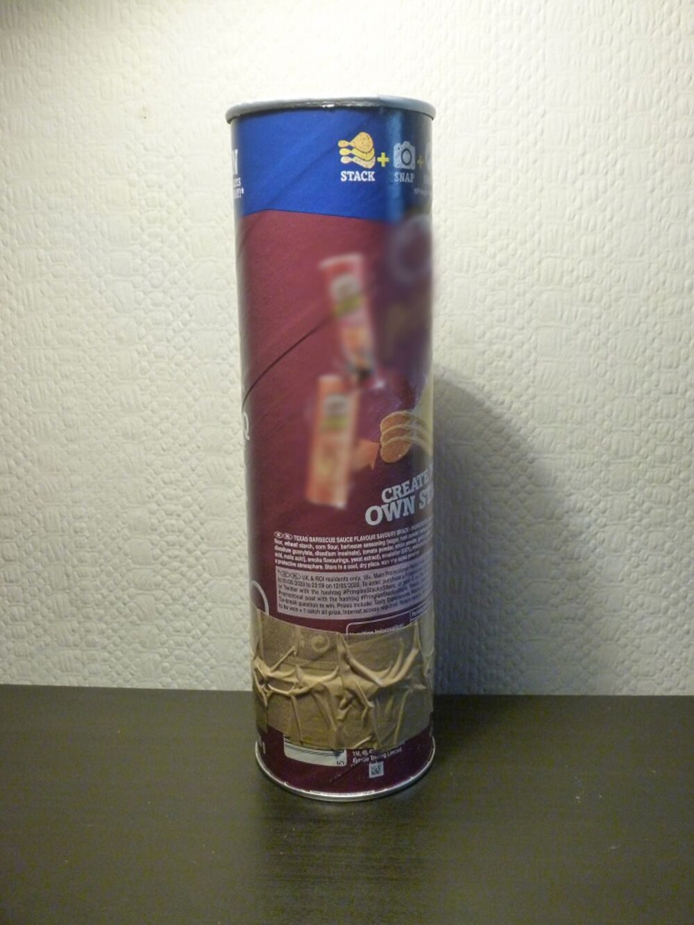 A Pringles tube cut into two pieces and taped back together, on a black table.
