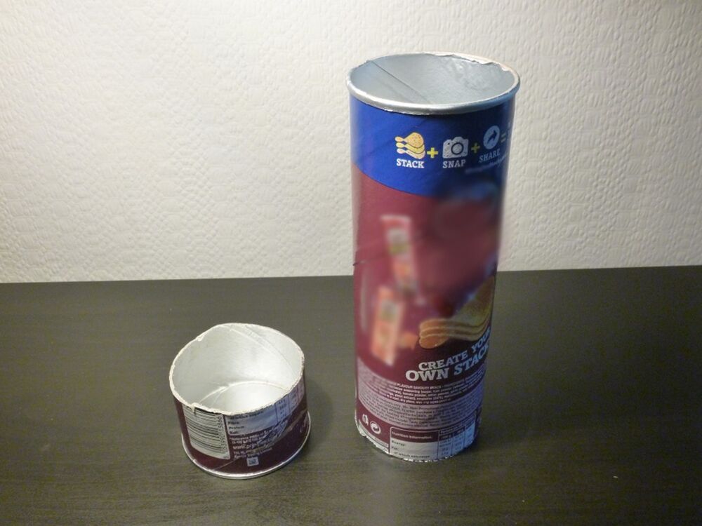 A Pringles tube cut into two pieces - one two inches long, the other eight inches - on a black table.