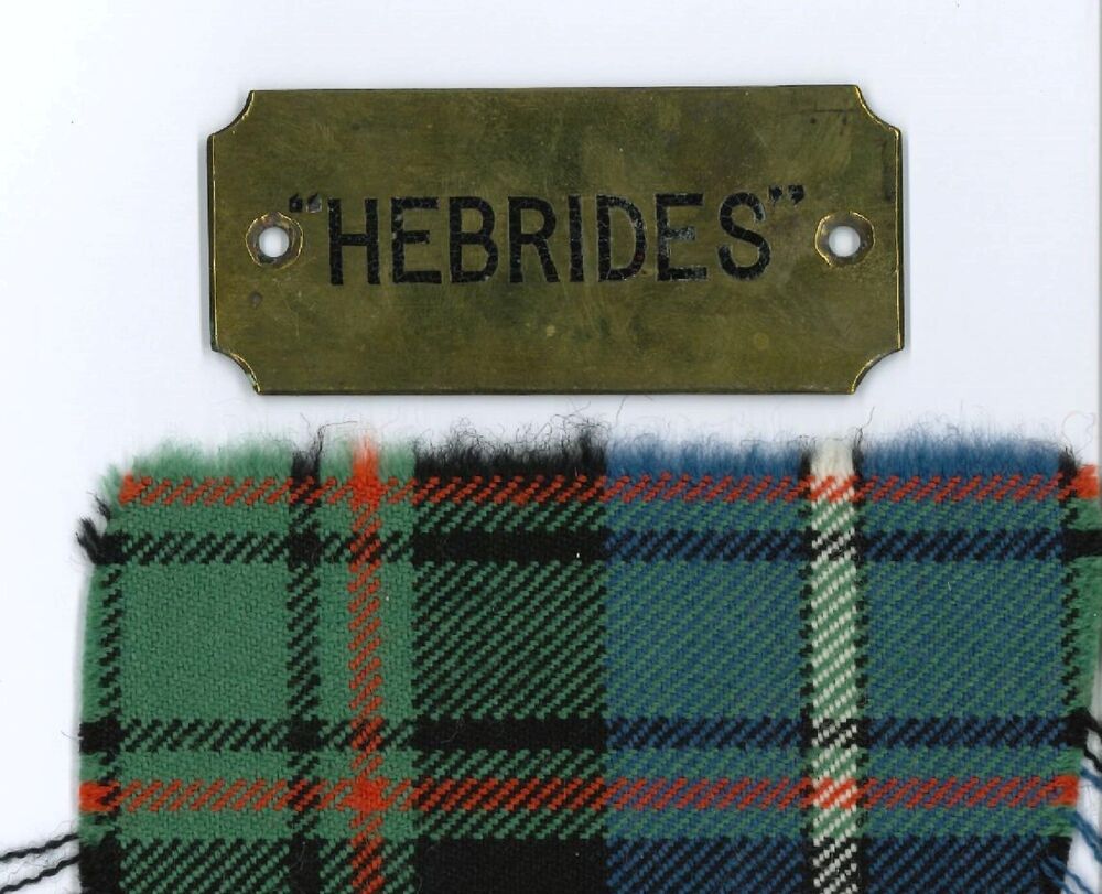 A brass nameplate with the word Hebrides, and a scrap of blue and green tartan underneath it.