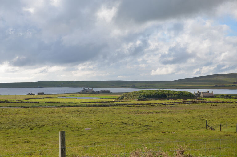 A fields with hills in the background and the sea.