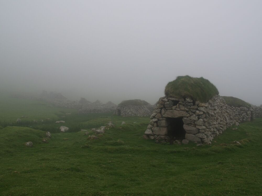 A row of cleitean on a St Kilda hillside, shrouded in mist.