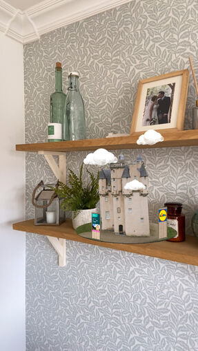 The new Craigievar Castle Instagram AR filter sits on a shelf amongst other decorations, with a patterned wallpaper behind.