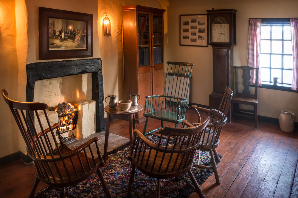 The interior of Bachelors’ Club, including a fireplace, four chairs and a grandfather clock
