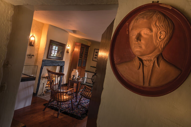 The interior of Bachelors’ Club, with a portrait of Robert Burns. Through the doorway is a fireplace and four chairs