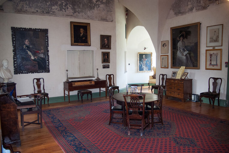The Great Hall at Alloa Tower. A round wooden table with dining chairs stands in the centre of the room. Family portraits hang on the walls.