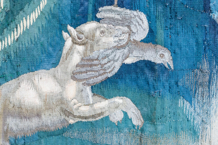 Detail in a tapestry of a hunting dog catching a bird, after cleaning