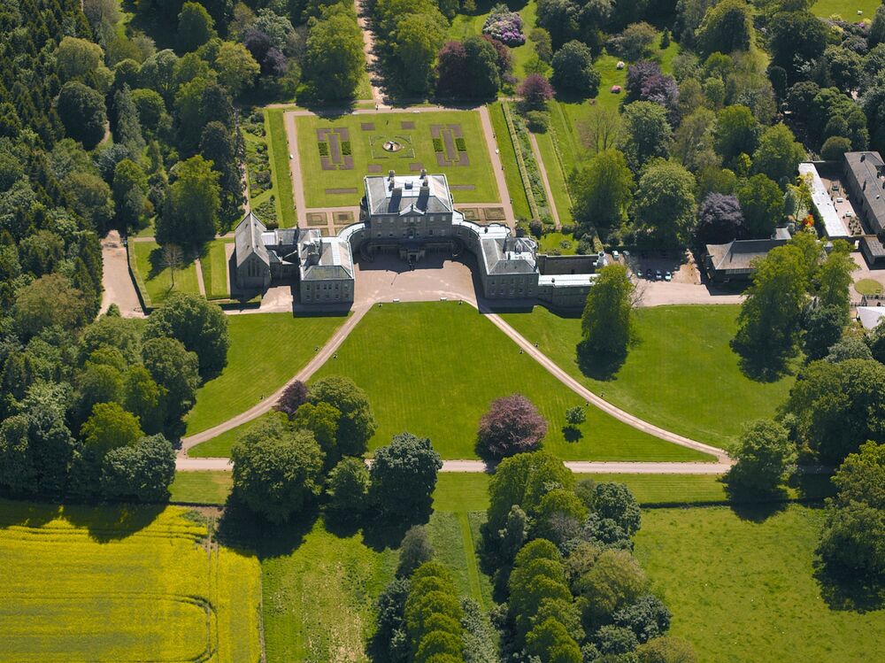 An aerial view of Haddo House, showing its Georgian symmetrical design. It is surrounded by tall trees, large lawns and a country park.