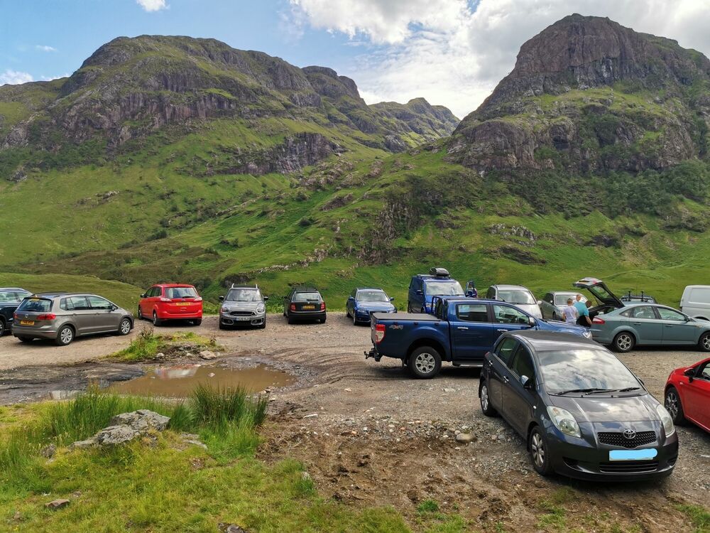 A crowded car park in a mountainous landscape.