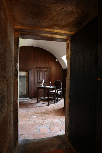 A doorway and beyond a brick-floored room with table and chair