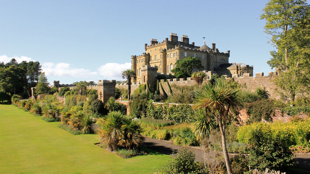 A view of Culzean Castle on a sunny day, looking up from the manicured lawns and flower beds in the Fountain Court.