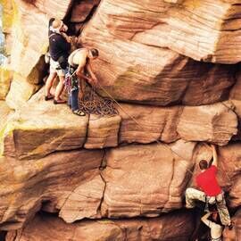 Three men climbing a rockface