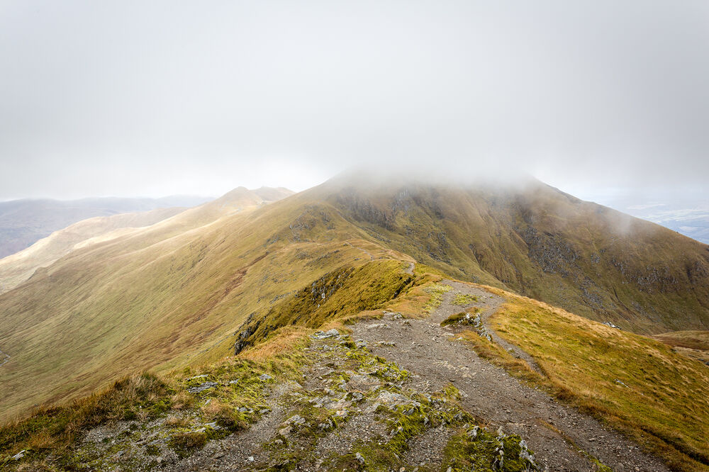 Mist blanketing the peak of Ben Lawers, with a ridge path running into the foreground.