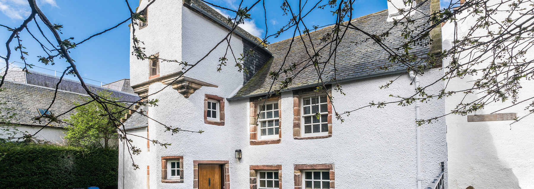 An old white townhouse with a grey slate roof and a wooden door.