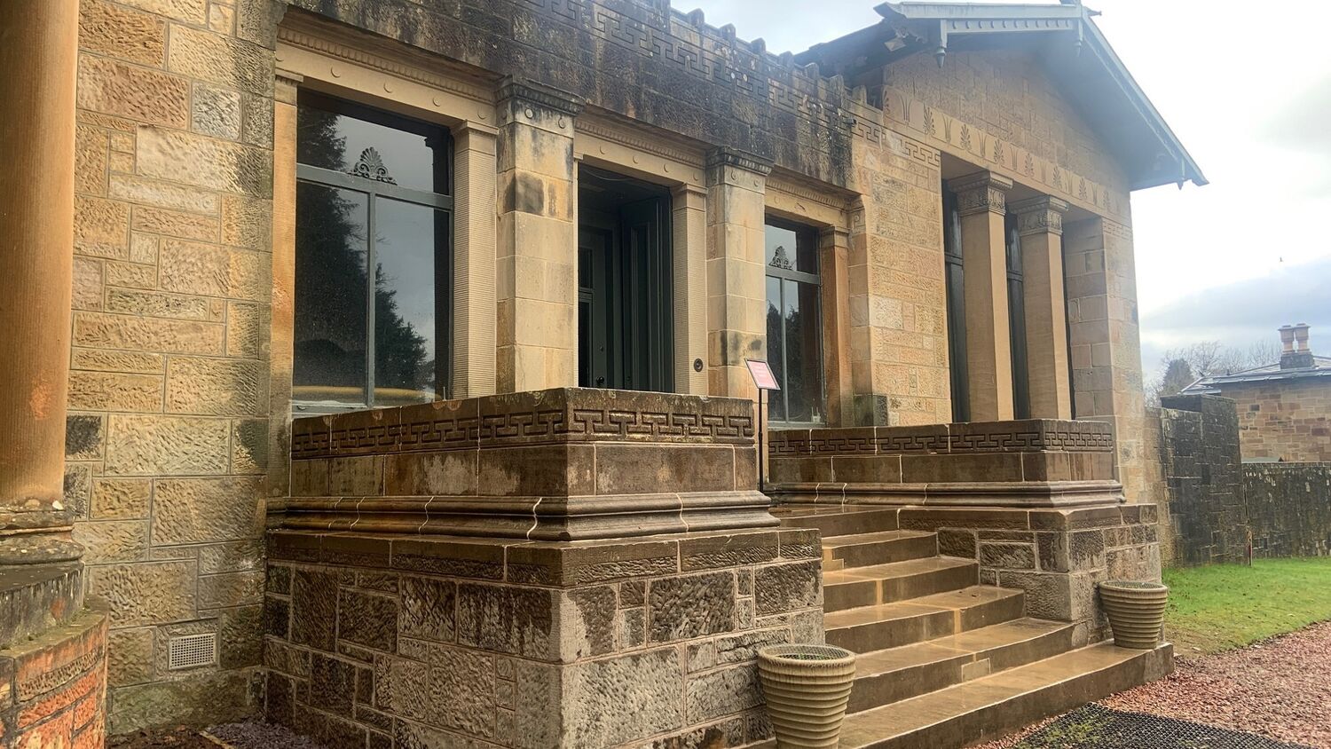 The main entrance to Holmwood on a rather wet day. The stone steps and surrounding walls leading to the front door have recently been cleaned. Two stone urns stand either side of the bottom step.