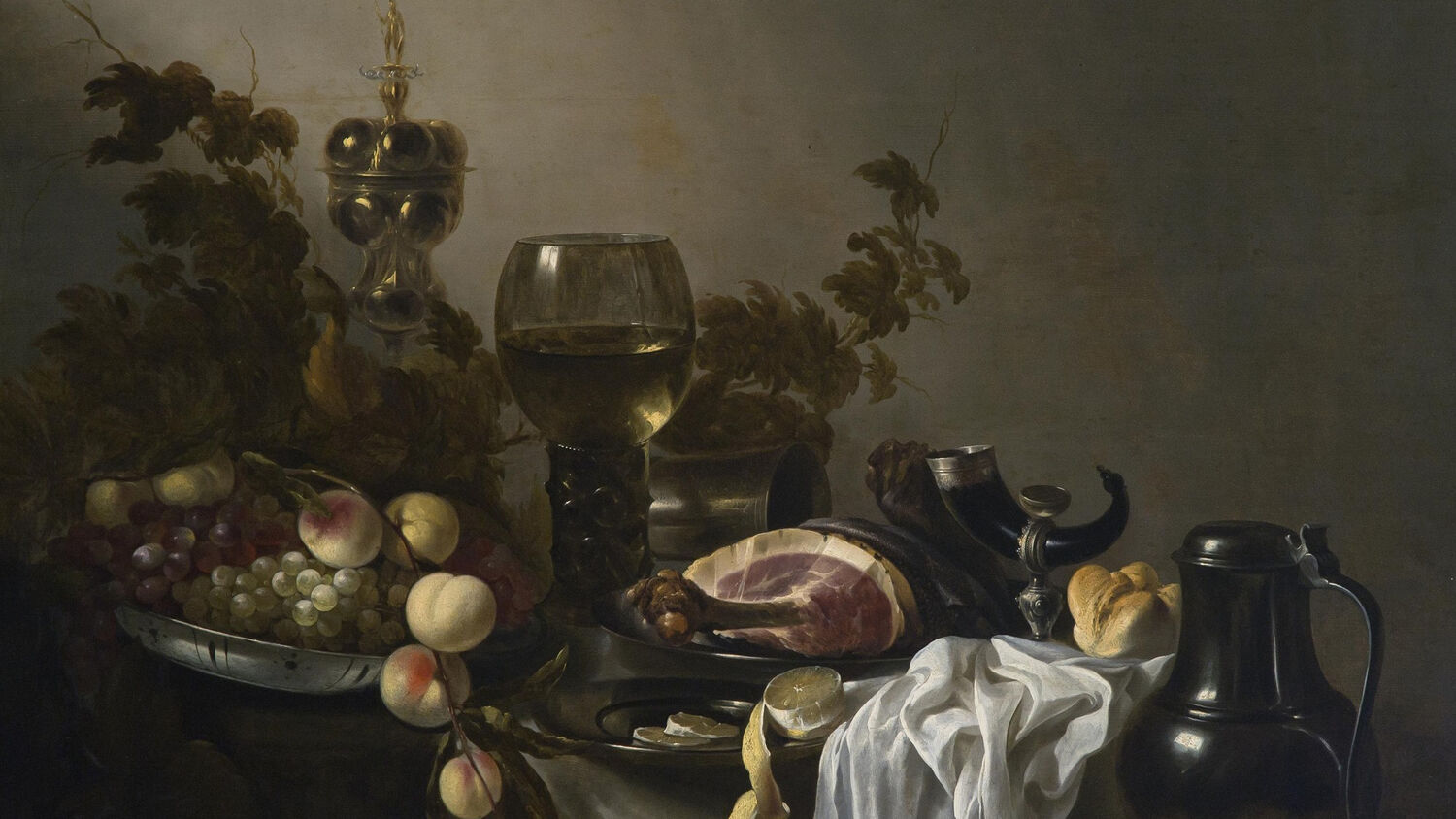 A close-up view of an oil painting of a still life, featuring peaches, grapes and a ham bone arranged on a table with a white cloth. There are several drinking vessels on the table too, as well as some leafy branches in the background. The blue Naked Wines logo can be seen in the bottom left corner.