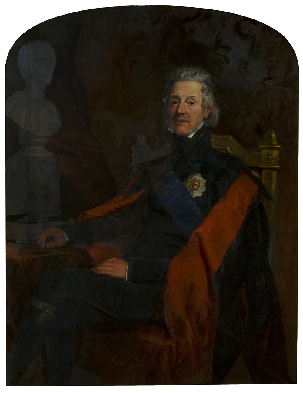 A portrait oil painting of an older man seated on a wooden chair, with his legs crossed. He wears a formal military-style uniform with a dark jacket with a very high collar, and a blue sash across his body. He also wears a black and red cape over his shoulders, which falls behind him.