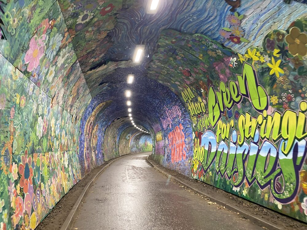A lit old railway tunnel is decorated in brightly painted murals.