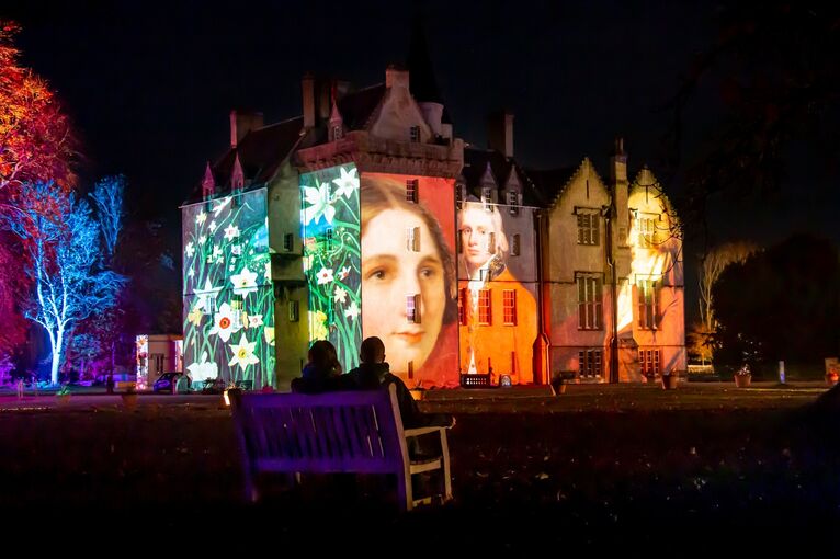 A view of the exterior of Brodie Castle at night, lit by giant projected images on the walls.