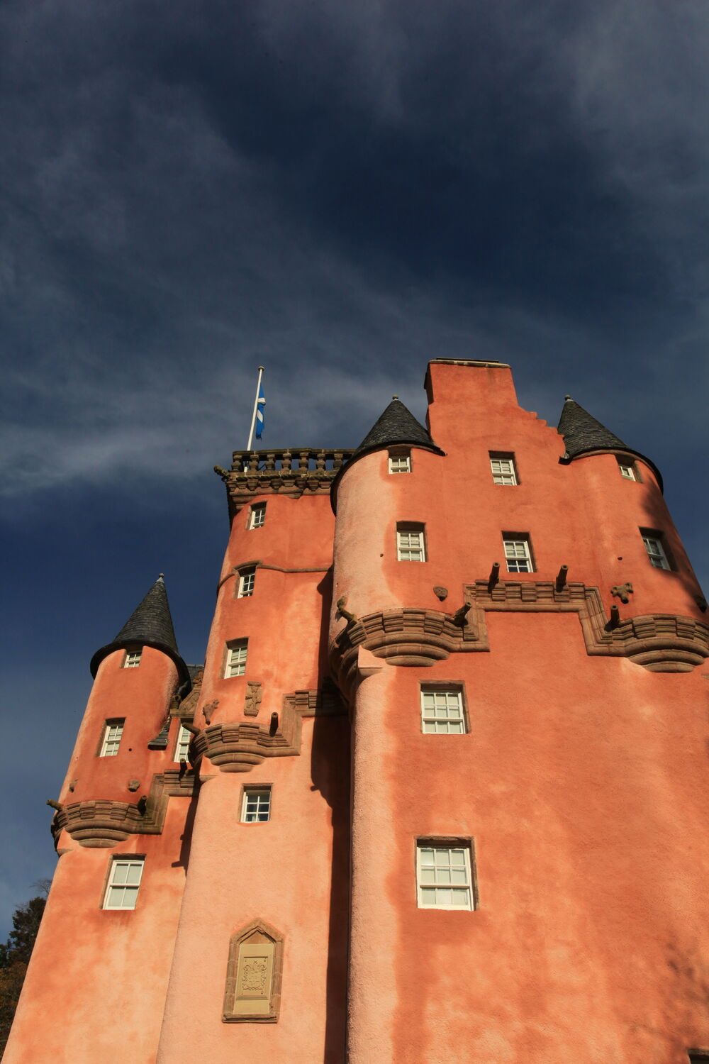 A close-up of Craigievar Castle's iconic pink walls against a blue sky.