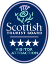 A navy oval badge from the Scottish Tourist Board, showing 4 stars for a Visitor Attraction. There is an illustrated green and purple thistle at the top of the badge.